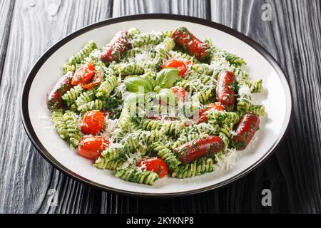 Saucisse de pesto vert pâtes avec tomates et parmesan sur l'assiette de la table. Horizontale Banque D'Images