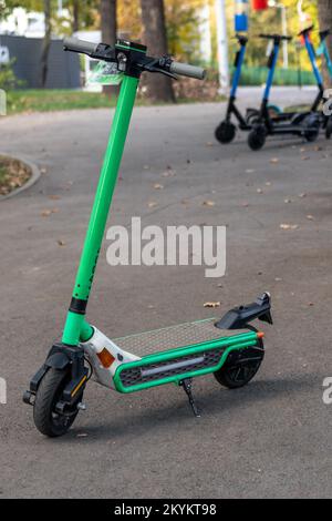 Parking pour scooters électriques dans l'espace de loisirs de la ville d'automne. E-scooter public, transports verts populaires Banque D'Images