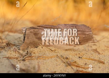 Concept, affaires et finances. Dans le sable sur le fond de l'herbe jaune il y a un signe avec l'inscription - TEMPS POUR LE FEEDBACK Banque D'Images