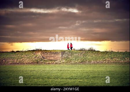 Deux femmes portent toutes deux un chien de marche rouge le long du sentier côtier de Knott End, Preesall, Royaume-Uni Banque D'Images