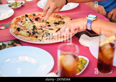 Pizza à couper les mains à partager dans une table de restaurant. Banque D'Images