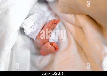 Le sacrement du baptême d'un bébé dans l'église, les jambes du bébé sur une feuille blanche. Banque D'Images