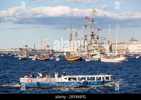 Saint-Pétersbourg, Russie-circa Jul, 2021: Un bateau touristique pour marcher le long de la rivière passe par des voiliers dans les eaux de la Neva, St. Saint-Pétersbourg Banque D'Images