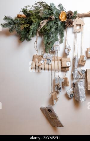 Un calendrier de l'Avent de Noël avec des cadeaux et des décorations est fixé sur un mur blanc dans une pièce. Photo verticale Banque D'Images