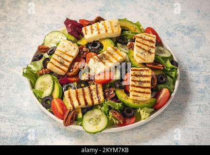 Cuisine grecque - salade avec fromage d'halloumi grillé, avocat, noix de pécan et tomates. Banque D'Images