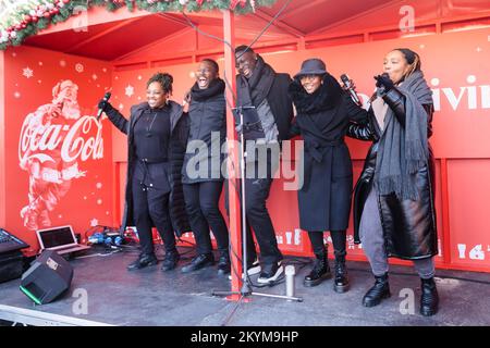 Wembley Park, Londres, Royaume-Uni. 1st décembre 2022. Le Choeur Coco Cola accueille les visiteurs en sérénade tandis que le célèbre camion de Noël Coca Cola s'arrête sur la voie olympique, en face du stade Wembley, lors de sa tournée britannique de 2022. En soutenant FareShare, Coca-Cola fera don de l'équivalent de milliers de repas, l'équivalent d'un repas offert au nom de chaque personne qui participe à la tournée de Noël Coca-Cola en camion cette année. Photo par Amanda Rose/Alamy Live News Banque D'Images