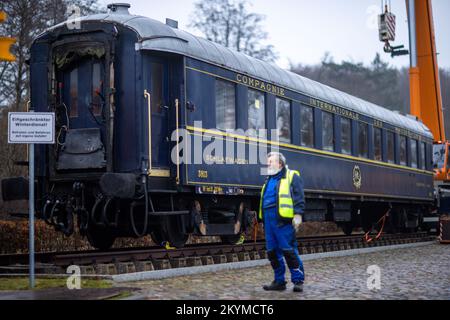 01 décembre 2022, Mecklembourg-Poméranie occidentale, Gadebusch: Un employé de grue se tient dans l'allée de la voiture de couchage 1941 de l'Orient Express légendaire, qui est maintenant garée sur la voie du musée à côté de la gare historique. Autrefois utilisé entre Paris et Istanbul, le chariot de 54 tonnes a été soulevé par deux grues montées sur camion de la voie d'exploitation du Deutsche Bahn dans la zone du musée pendant la nuit. Photo: Jens Büttner/dpa Banque D'Images