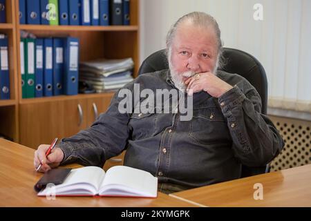 Portrait d'un homme d'affaires âgé pensif assis à une table dans le bureau Banque D'Images