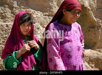 Bamyan (Bamiyan) / Afghanistan central : une femme et une jeune fille devant les falaises de Bamyan Banque D'Images