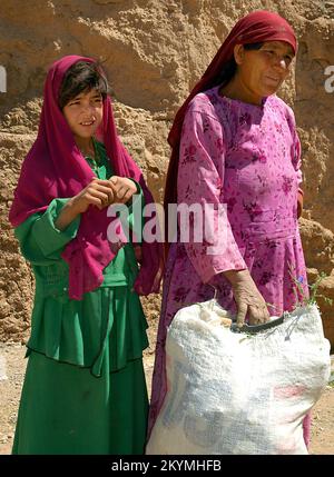 Bamyan (Bamiyan) / Afghanistan central : une femme et une jeune fille devant les falaises de Bamyan Banque D'Images