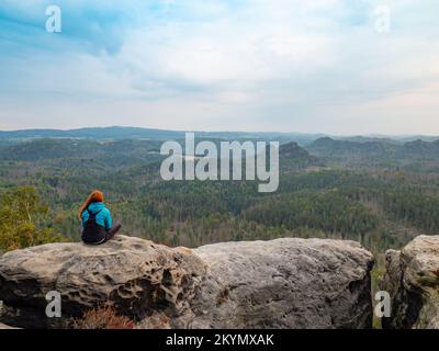 Paysage paisible. jolie fille assise sur les rochers, à loin et profiter de la nature. Vêtements de sport confortables sur son slim bod Banque D'Images