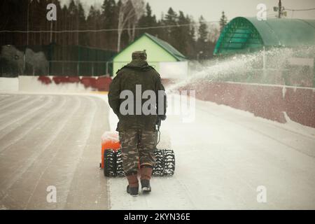 Déneigement à la patinoire. Élimination de la couche de neige de la glace. Le travailleur nettoie le stade de précipitation. Banque D'Images