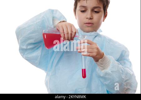 Détails: Mains de garçon d'école scientifique chimiste verse une substance chimique rouge de la fiole à fond plat dans un tube à essai Banque D'Images