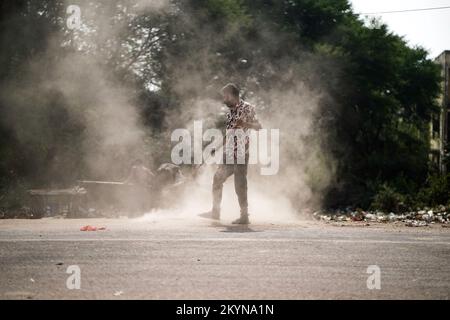 Homme balayant les ordures avec un balai et polyhthène côté rue ou route, homme nettoyant la zone polluée, jour de contrôle de la pollution, concept de pollution Banque D'Images