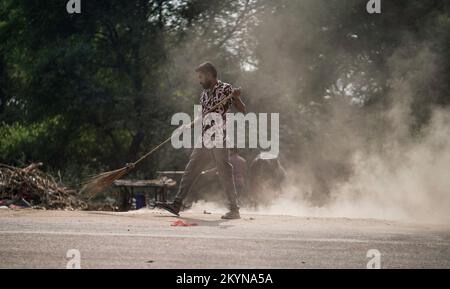 Homme balayant les ordures avec un balai et de la grande zone de déchets en polyhthène, homme nettoyant la zone polluée, journée de contrôle de la pollution, concept de pollution Banque D'Images