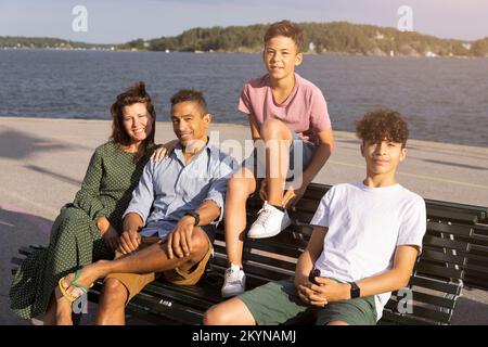 Portrait de famille souriante assis sur un banc près de la mer Banque D'Images