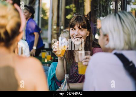 Bonne femme transgenre parlant tout en appréciant le jus avec des amis non binaires Banque D'Images