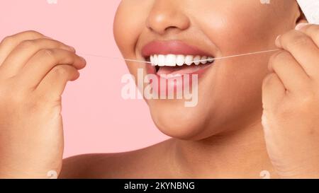 Concept de soins de la bouche et de soins de la bouche. Gros plan coupe courte d'une femme obèse noire non reconnaissable utilisant de la soie dentaire Banque D'Images
