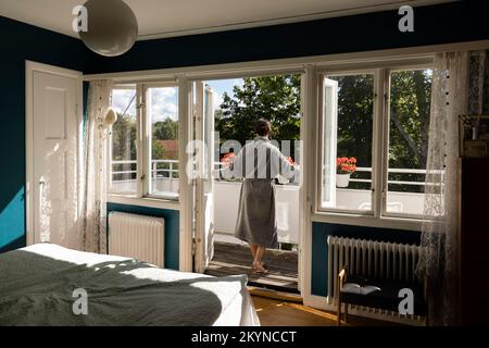 Vue arrière de la femme ouvrant les portes de la chambre tout en marchant dans le balcon Banque D'Images