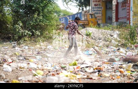 Homme balayant les ordures avec un balai et de la grande zone de déchets en polyhthène, homme nettoyant la zone polluée, journée de contrôle de la pollution, concept de pollution Banque D'Images