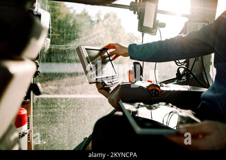 Main de l'exploitant exploitant de l'ordinateur assis dans le tracteur par beau temps Banque D'Images