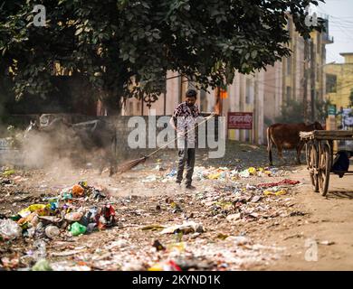 Décembre, 2022, Raipur, Inde: Homme balayant la poubelle avec un balai et de la polyhthène grande zone de déchets, homme nettoyant la zone polluée, contrôle de la pollution da Banque D'Images