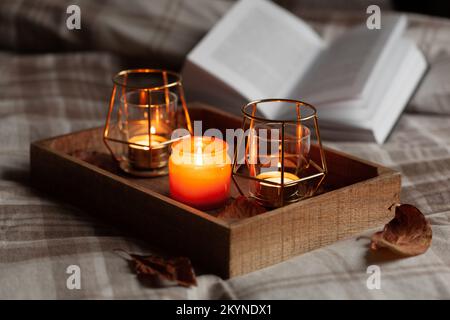 chambre chaleureuse et confortable hiver ou automne concept, bougies sur plateau et un livre Banque D'Images