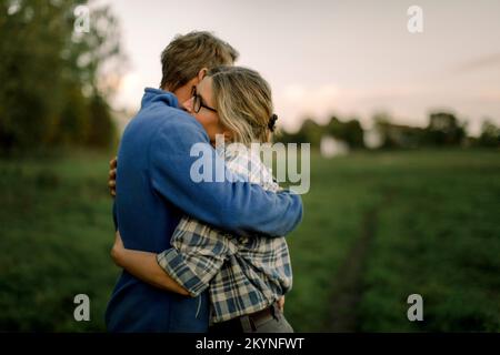 Couple d'âge mûr s'embrassant sur le terrain pendant le coucher du soleil Banque D'Images