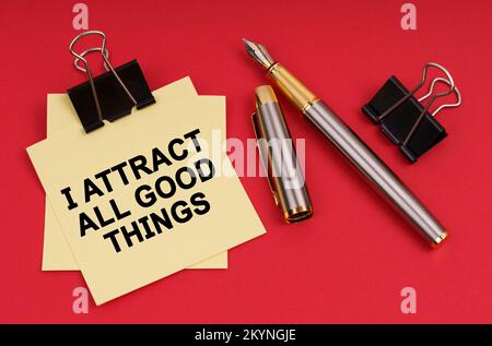 Concept d'entreprise. Sur fond rouge, un stylo et des autocollants avec l'inscription - j'attire toutes les bonnes choses Banque D'Images
