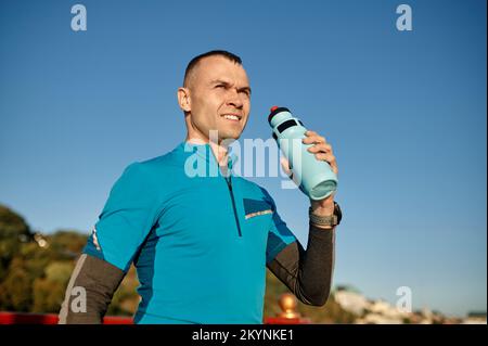 Portrait d'un homme d'âge moyen sportif tenant une bouteille d'eau pour se rafraîchir Banque D'Images