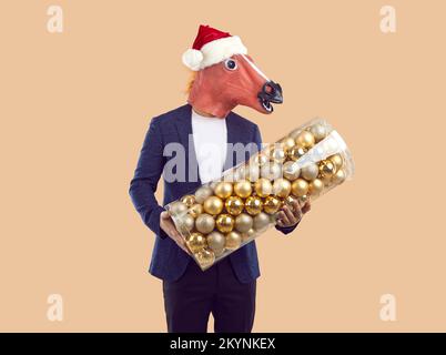 Portrait d'un homme portant un costume de cheval amusant tenant un grand ensemble de boules d'arbre de Noël Banque D'Images