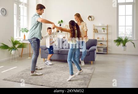 Bonne famille maman, papa, fille et fils jouant à la tête d'une danse ronde à la maison dans le salon. Banque D'Images