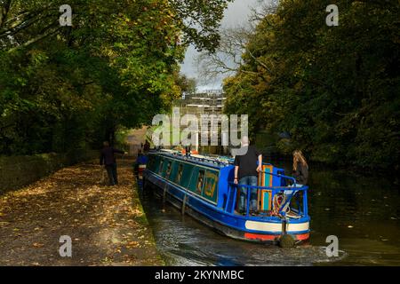 A la direction du timon, à bord d'un bateau à rames ensoleillé (feuilles d'automne du chemin de halage) - 5 écluses de montée, canal de Leeds et Liverpool, West Yorkshire, Angleterre, Royaume-Uni. Banque D'Images