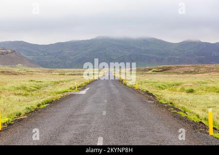 Continuez tout droit sur la route lonely en traversant la prairie sur l'Islande Banque D'Images