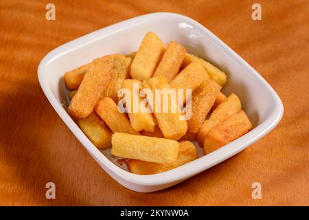 Manioc frit. Petite portion de copeaux dans un bol blanc sur fond de bois. Banque D'Images