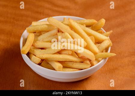 Frites. Petite portion de copeaux dans un bol blanc sur fond de bois. Banque D'Images