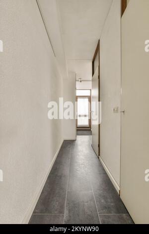 Intérieur de plat confortable dans un style minimaliste avec couloir vide étroit éclairé par des lampes Banque D'Images