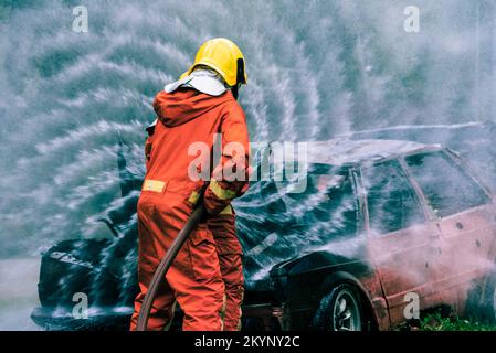 Pompier formation de sauvetage pour arrêter de brûler des flammes, pompier porter un casque et un uniforme de sécurité pour la protection brûler en utilisant le tuyau avec de l'eau chimique FO Banque D'Images