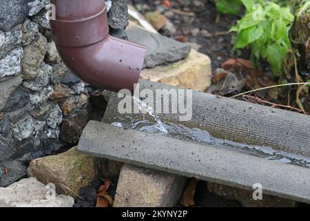 De l'eau de pluie s'écoule du tuyau de caniveau. Système de caniveaux sur le toit de la maison rurale. Banque D'Images