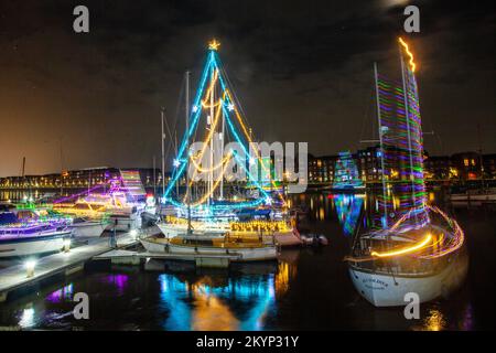 Lumières de Noël en mer. Une brillante parade de bateaux de vacances à Preston, Lancashire décembre 2022. Yachta et voiliers amarrés décorés de lumières de Noël étincelantes à Preston Marinaa. Une soirée de Noël s'allume pour les foules qui bordent le mur du quai tandis que les porte-couchettes illuminent leurs bateaux et profitent d'une voile en soirée sous les lumières festives. Banque D'Images