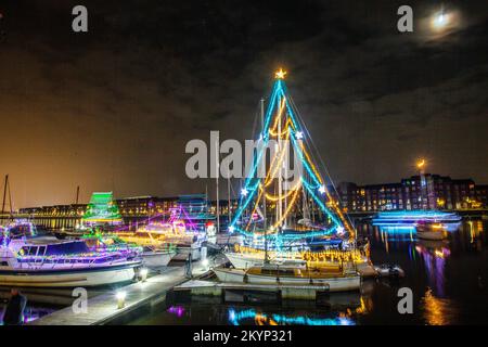 Lumières de Noël en mer. Une brillante parade de bateaux de vacances à Preston, Lancashire décembre 2022. Yachta et voiliers amarrés décorés de lumières de Noël étincelantes à Preston Marinaa. Une soirée de Noël s'allume pour les foules qui bordent le mur du quai tandis que les porte-couchettes illuminent leurs bateaux et profitent d'une voile en soirée sous les lumières festives. Banque D'Images