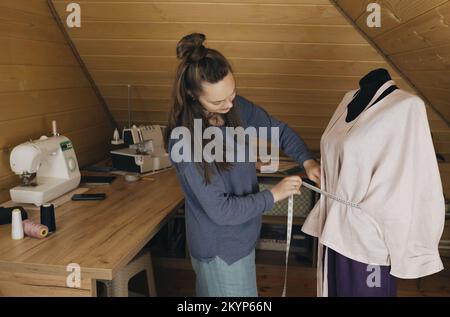 Un designer de mode prend des mesures pour un nouveau costume fait main dans un atelier. Petite entreprise. Banque D'Images