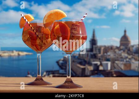 Deux verres de cocktail Spritz avec vue sur le port de la Valette et la vieille ville de la Valette, Malte. Banque D'Images