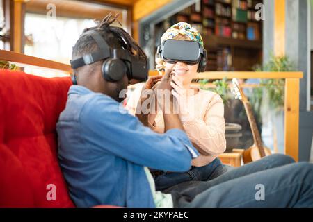 Des amis multiethniques se rencontrent en réalité en 3D sur le canapé rouge - Nouveau concept de technologie wearable Banque D'Images