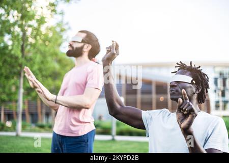 Amis multiculturels utilisant des lunettes futuristes de réalité augmentée sur un parc de la ville Banque D'Images