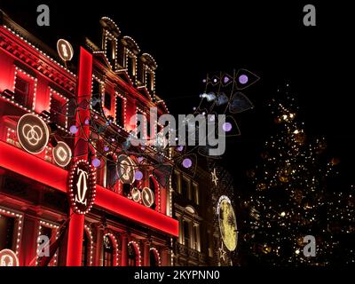 Cartier Jewellery Store présentoir de Noël avec effet ruban sur New Bond Street avec un arbre de Noël en premier plan, Londres. Banque D'Images