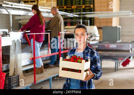 Femme tenant une boîte de fraises à l'entrepôt de fruits Banque D'Images
