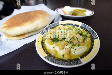 Houmous servis avec du pain pita et des légumes. La sauce épicée peut être ajoutée à ce favori du Moyen-Orient. Banque D'Images