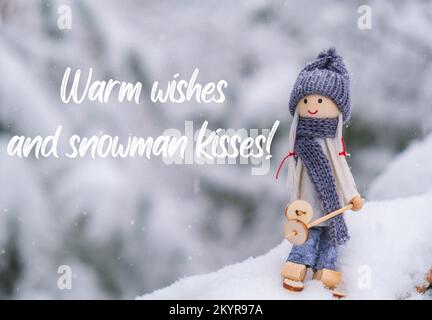 Voeux chaleureux et bonhomme de neige kisses inspiration plaisanterie citation phrase Angel gnome dans le foulard et chapeau tricoté ski sur la branche de sapin enneigé jouet Elf sur les skis dans le paysage enneigé Nouvelle année et carte de vœux de Noël joyeux. Vacances d'hiver Banque D'Images