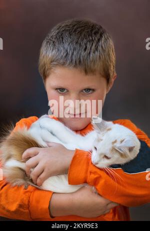 un jeune garçon doux tient un gros chat blanc, son animal de compagnie préféré Banque D'Images